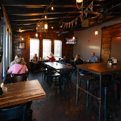Interior with mixed seating, rustic wooden walls and lighting from pendant fixtures.