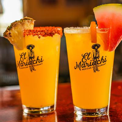 Two cocktails garnished with pinneapple and watermelon.