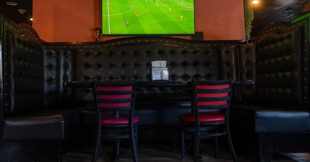 Interior, leather booth, table and chairs with TV on the wall