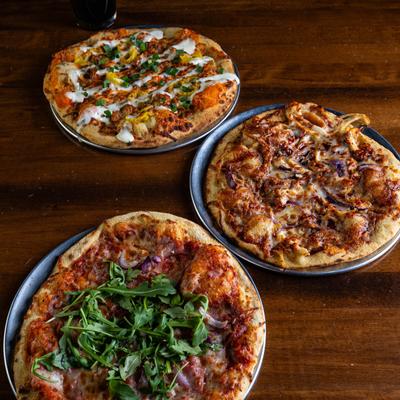 Prosciutto Special, Bourbon BBQ Chicken and Buffalo Chicken pizza on a table.