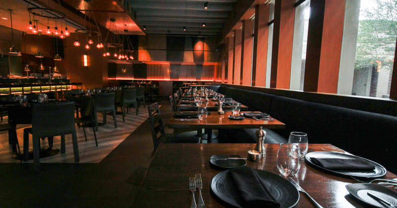 Interior, dim lit dining area with set tables and seating