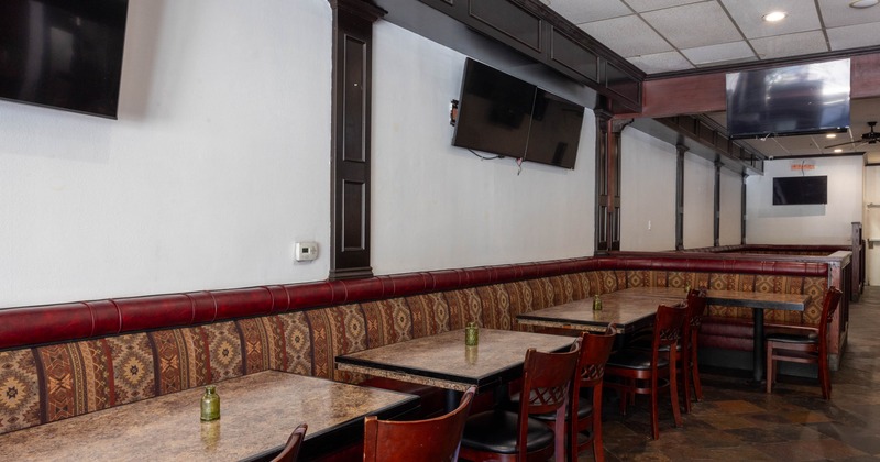 Interior of a restaurant featuring booth seating with patterned upholstery, dark marble tables