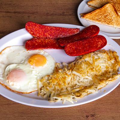 Fried eggs with hash browns, sausages, and toasted bread.