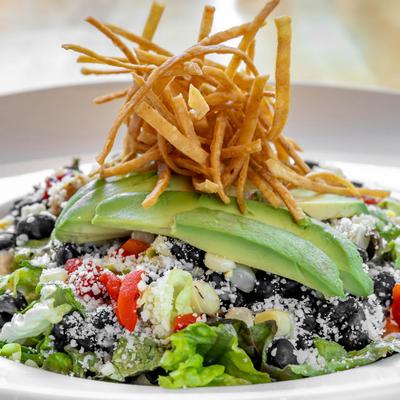 Santa Fe salad with black beans, cotija cheese, avocado, and crispy tortilla strips.