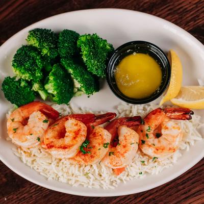 Shrimp with rice, broccoli, butter sauce, and lime wedges.