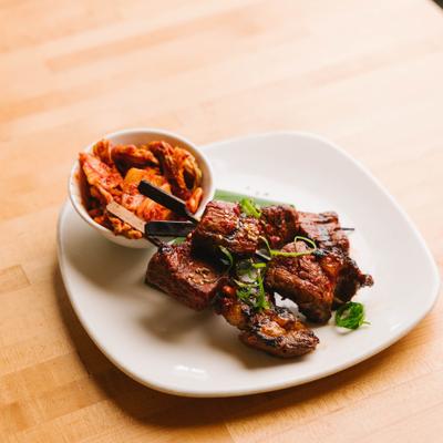 Kochujang beef skewers served with a side of kimchi.