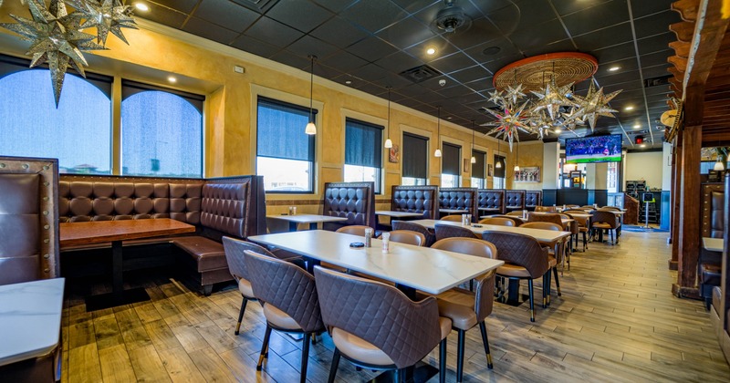Interior of a modern restaurant with leather booths, star-shaped lights, and a large TV