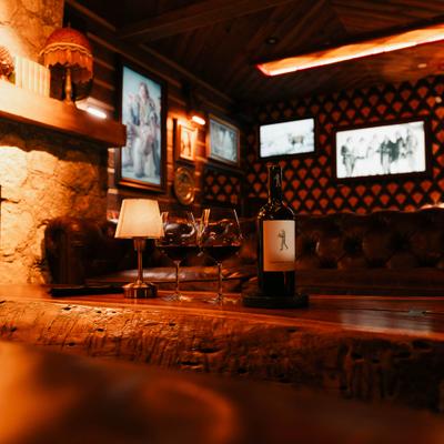 Cozy rustic lounge featuring a wooden table with two glasses and a wine bottle.