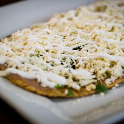 Huarache topped with cheese and crema drizzle.