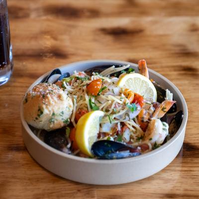 Seafood pasta with mussels, shrimp, calamari, cherry tomatoes, lemon wedges and garlic bread.