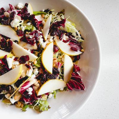 Mixed greens salad with sliced pieces of apple, top view