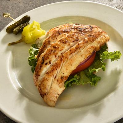 Fresh Pan Fried Grouper Sandwich on lettuce red onion and tomato.