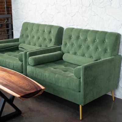 Interior, green tufted sofas beside a wood table.