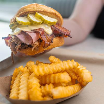 Pulled pork sandwich, with smoked ham, bacon, pepper jack cheese, pickles, and fries.