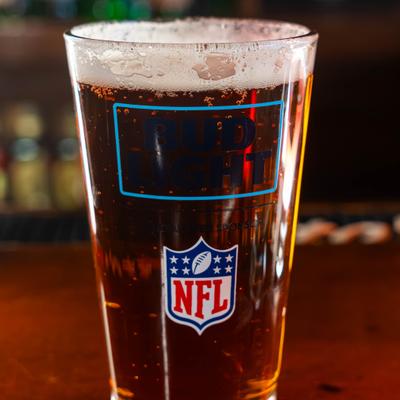 Glass of beer with foam and NFL logo on bar