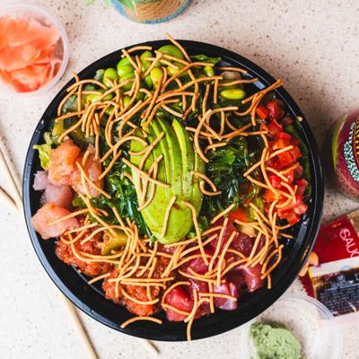 Tuna poke bowl, with lettuce, cucumber, edamame, seaweed, avocado, tomato, and spicy sauce.