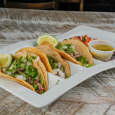 Portion of tacos with dip and sides.