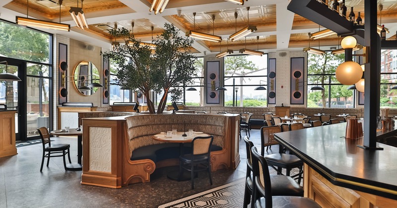 Modern interior with a circular booth, black bar, golden ceiling tiles, and large windows