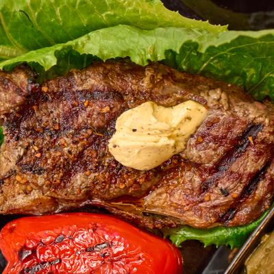 Grilled beef steak topped with compound butter, close-up