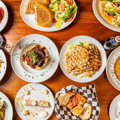 Spread of Italian dishes on a wooden table, accompanied with drinks, top view.