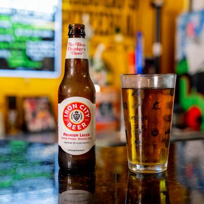 A bottle of lager and a filled pint glass sit on a glossy bar counter.