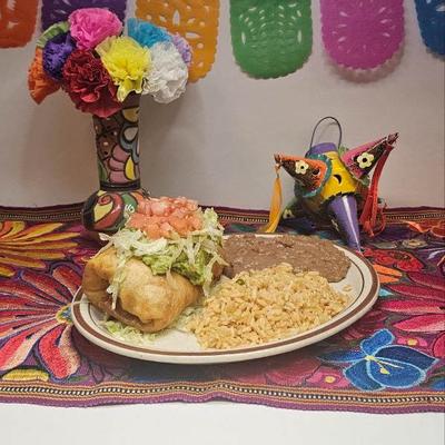Chimichanga topped with guacamole, lettuce, tomato, served with rice and beans.