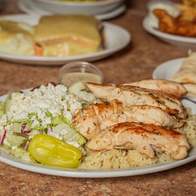 Grilled chicken plate with rice, fresh salad, cheese crumbles, and pepper.