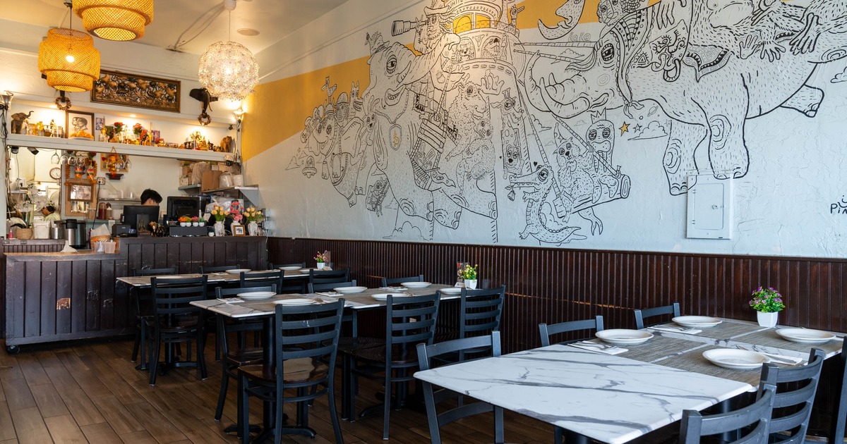 Interior with tables, chairs and a large mural of whimsical creatures.
