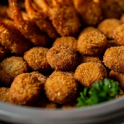 Breaded shrimp and bites with parsley garnish in a metal bowl.