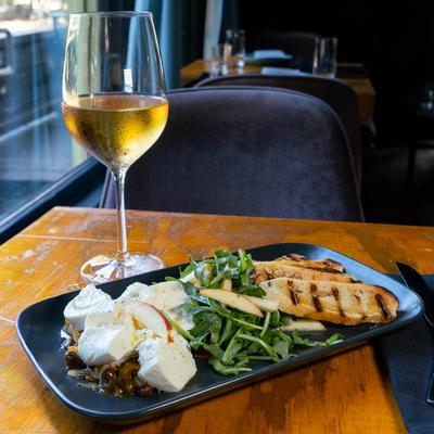 Burrata served with apricot and pistachio jam, apple, arugula, toasted sourdough, and wine.