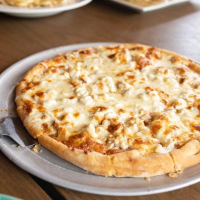 Chicken Alfredo Pizza served on a round metal tray.