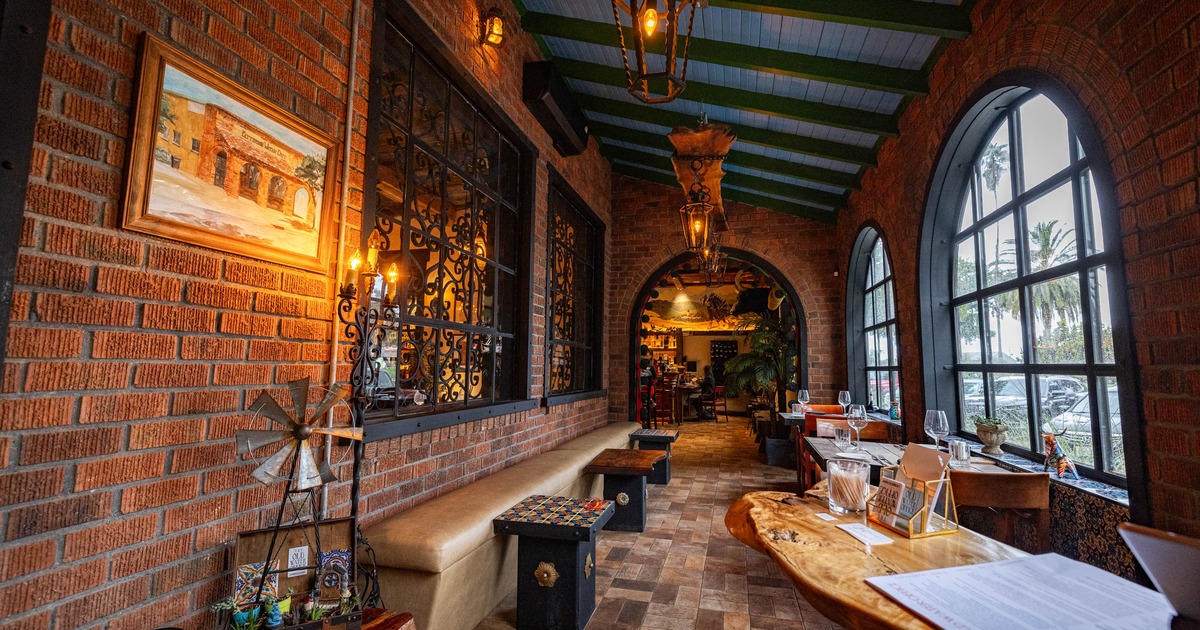 A cozy restaurant corridor with brick walls, arched windows, wooden tables