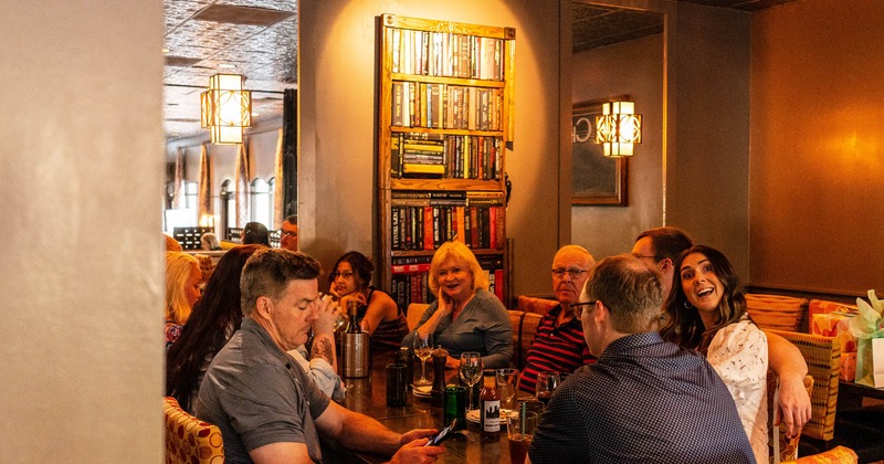 Dining room, guests sitting, bookshelf behind