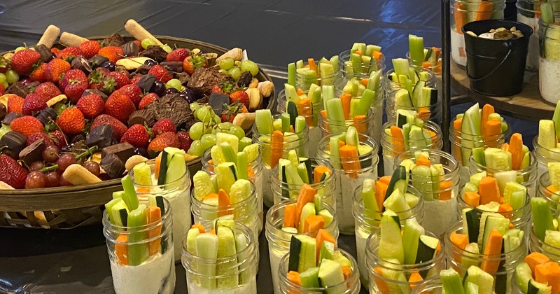 Numereus individual servings of veggie dip cups alongside a platter of food