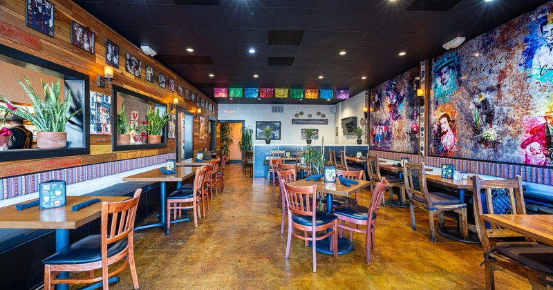 Interior, decorated seating area with wooden tables and chairs, art on the walls