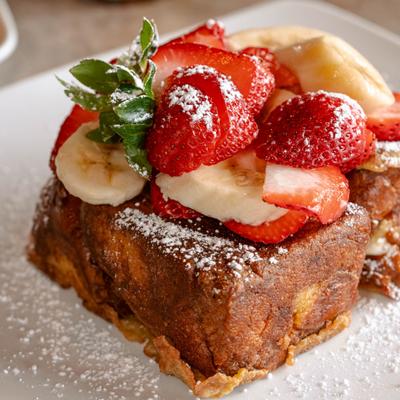 Stuffed French toast topped with strawberries, banana and powdered sugar.