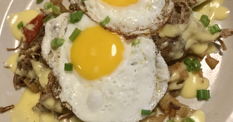 Two fried eggs with scallion, served over pulled meat and melted cheese