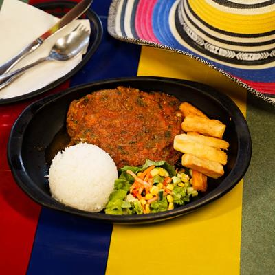 Flank steak with Colombian sauce, served with white rice, fried yuca and salad.
