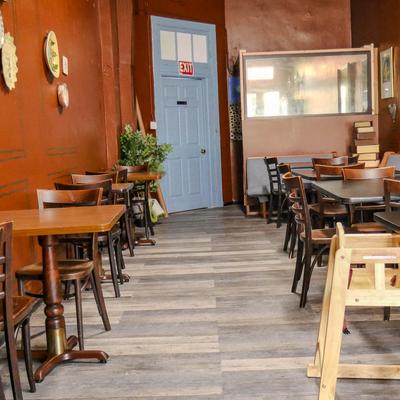Interior with wood-style flooring, wooden tables, wall decorations and entrance area.