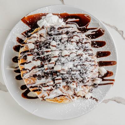 Oreo Smores Pancakes topped with whipped cream and drizzled with chocolate.