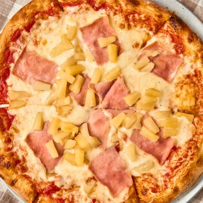 Hawaiian Pizza topped with diced pineapple and ham slices.