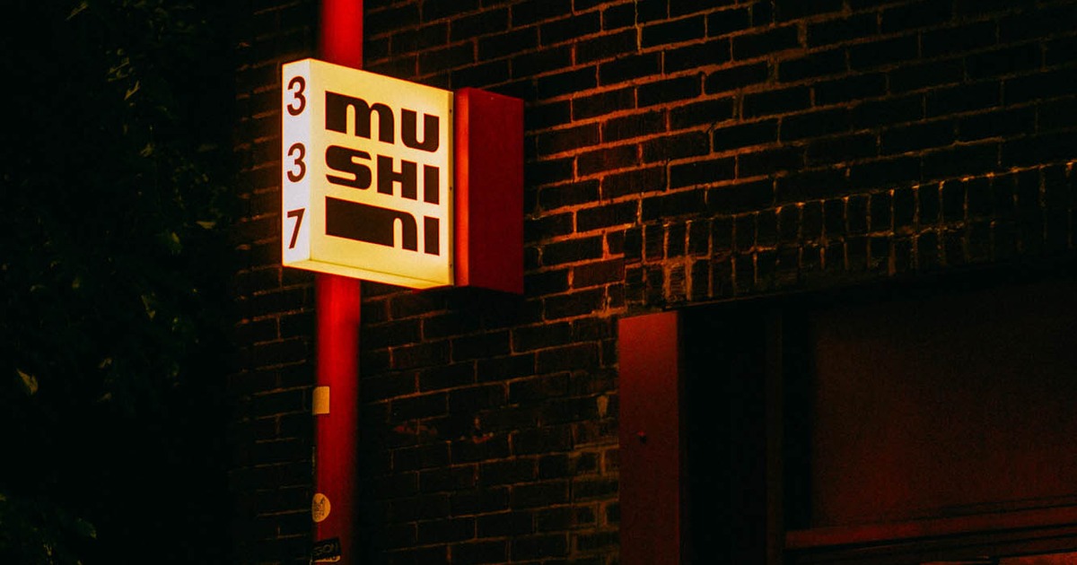 Illuminated restaurant sign on a dark brick building