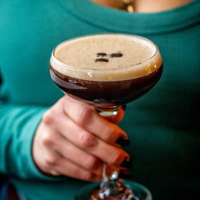 A hand holding an espresso martini.