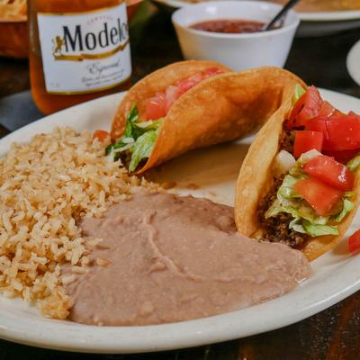 Two tacos with rice and refried beans.