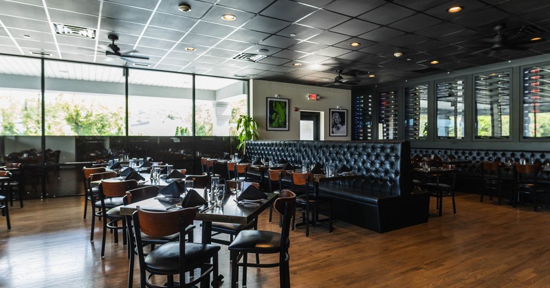 Interior view of a stylish restaurant with wooden floors, dark booths, and large windows