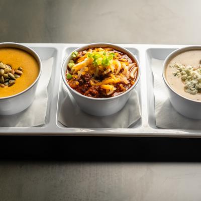Soup flight with three bowls of assorted soup.