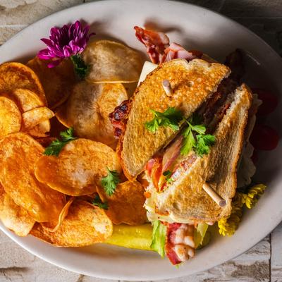 Club sandwich with crispy bacon, lettuce, and tomato, served with chips.