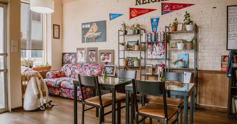 Interior, seating area, tables for two, colorful two seater sofa in the corner, shelves with decor