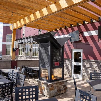 Sunlit patio with metal furniture and string lights under a wooden pergola.