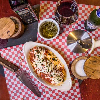 A bowl of meatballs surrounded by wine, beer, olive oil, and spices.